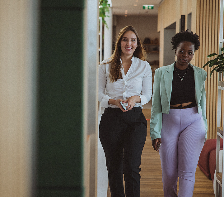 Zwei Personen gehen im Office nebeneinander den Gang entlang.