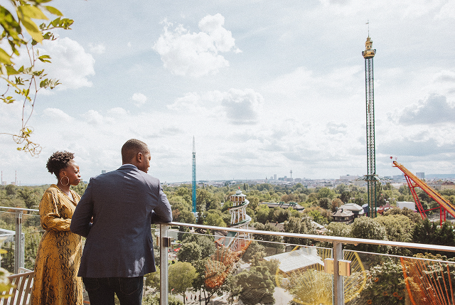 Zwei Personen stehen auf einer Terrasse mit Ausblick auf Wien und schauen in die Ferne